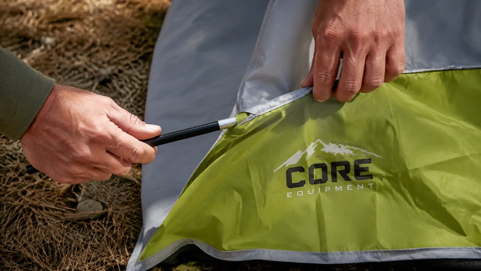 Outdoorsman threading a fiberglass pole through the CORE dome tent sleeve at a campsite