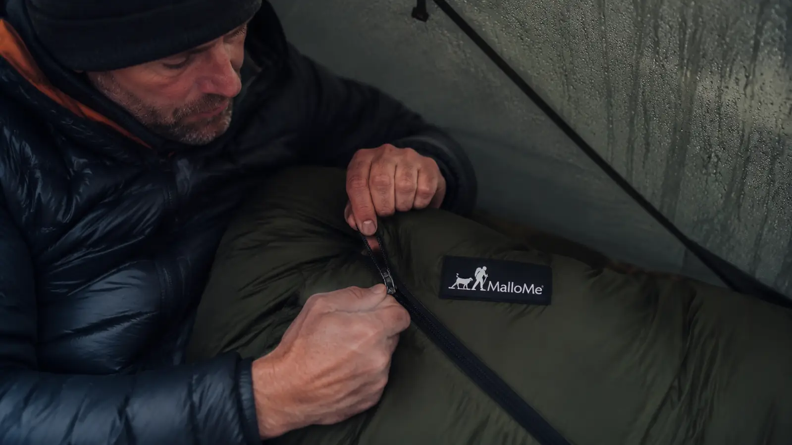 Close-up of the MalloMe sleeping bag zipper being pulled closed with gloved hands
